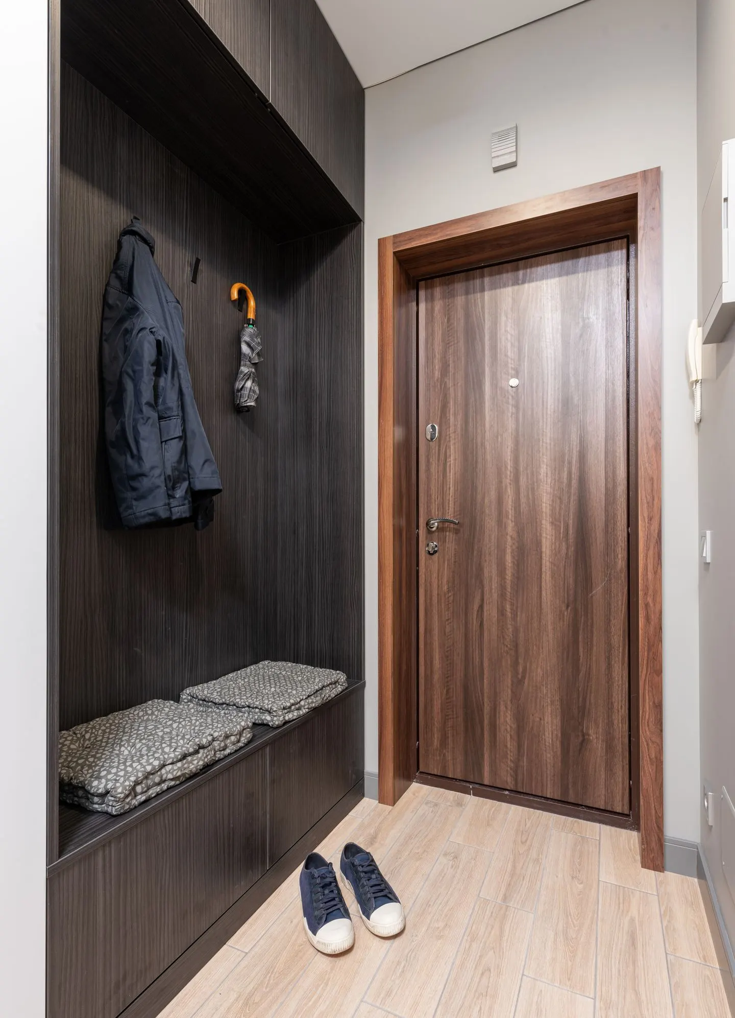 Heller Eingangsbereich mit Garderobe und geschlossener Tür.
