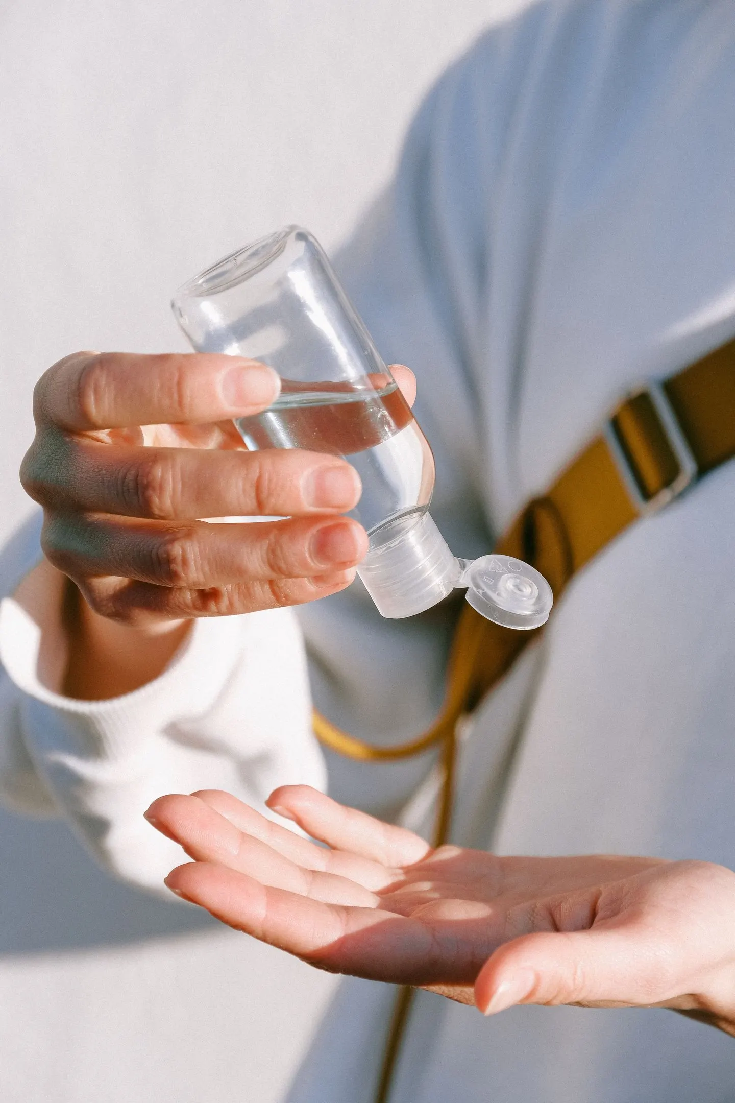Hände mit einer umgedrehten transparenten Flasche über einer geöffneten Hand.